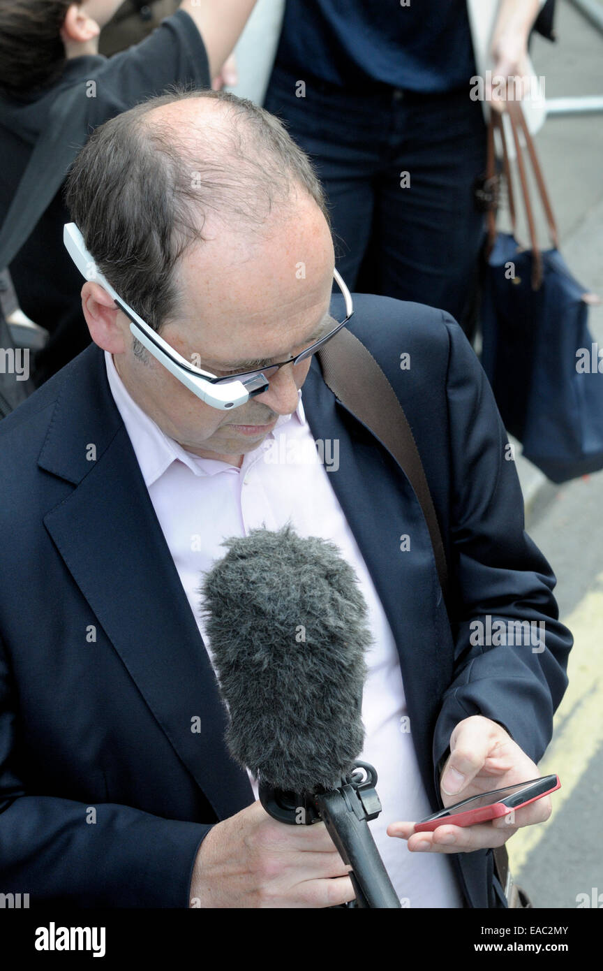 Rory Cellan-Jones, BBC's Technology Correspondent, reporting in central London,wearing Google Glass and using his mobile phone Stock Photo