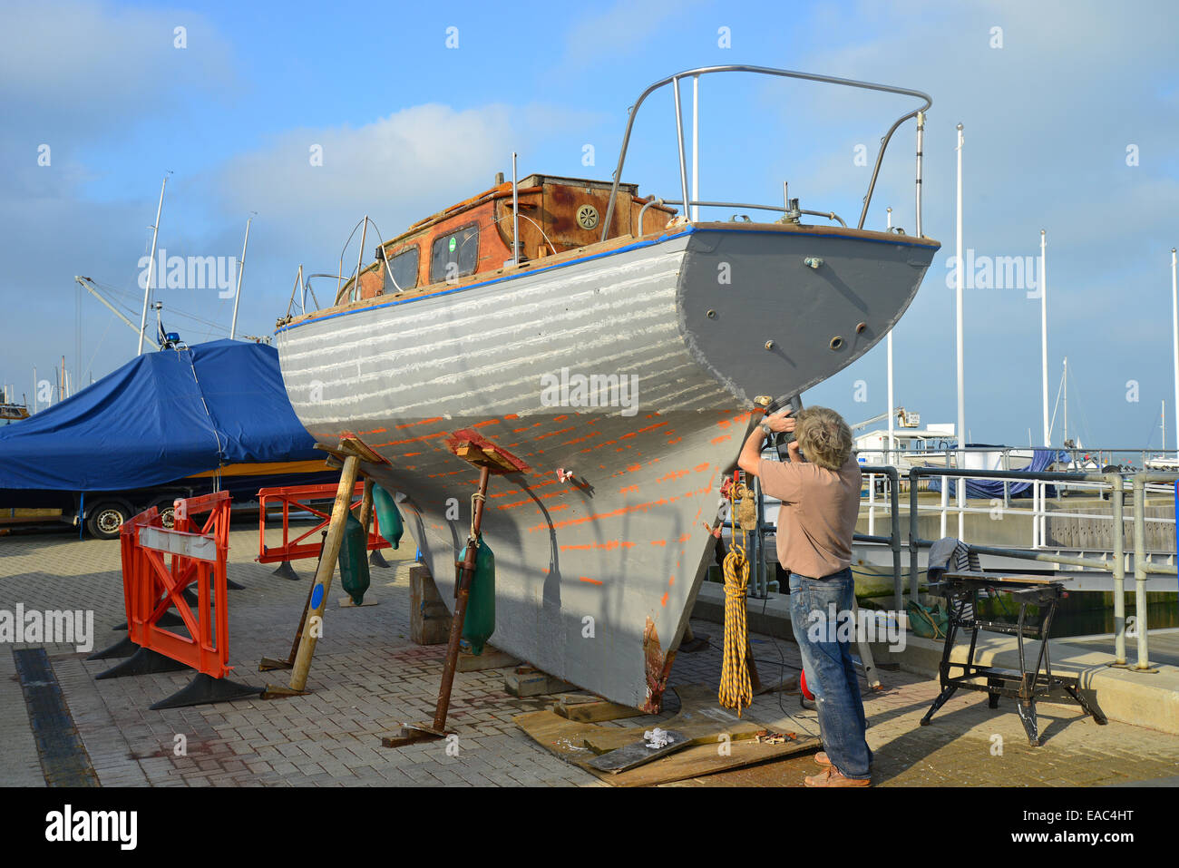 Man fixing keel of old wooden yacht, Cowes Harbour, Cowes, Isle of Wight, England, United Kingdom Stock Photo