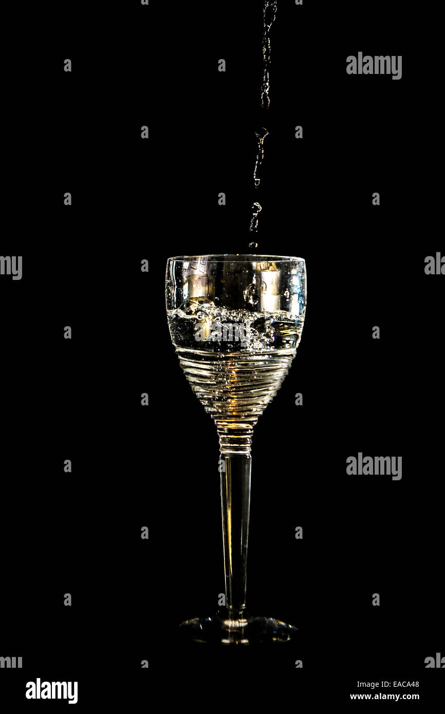 White wine is poured into a crystal wine glass Stock Photo