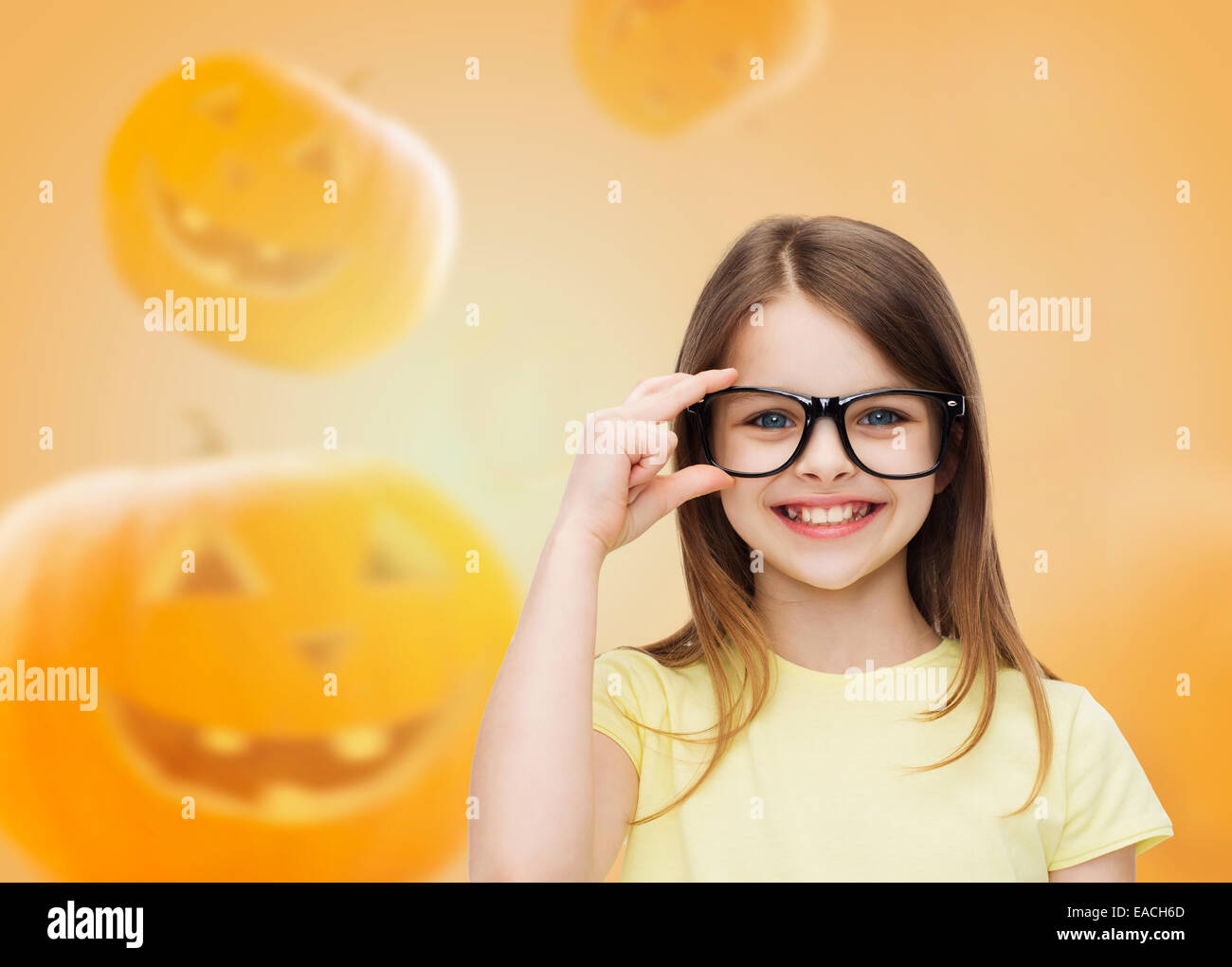 smiling girl in glasses over pumpkins background Stock Photo