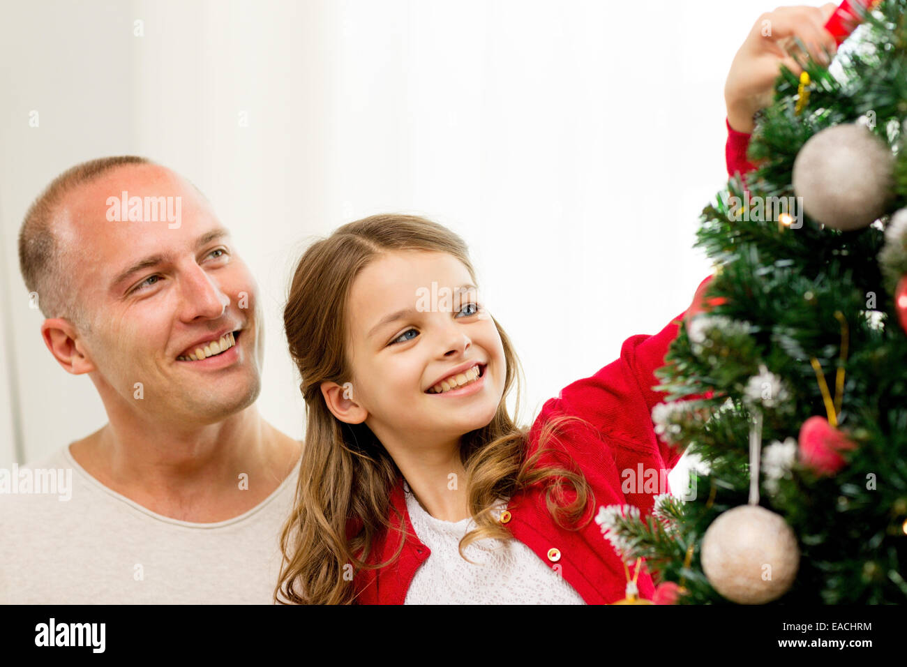 smiling family decorating christmas tree at home Stock Photo
