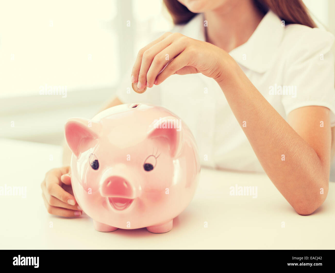 smiling child putting coin into big piggy bank Stock Photo - Alamy