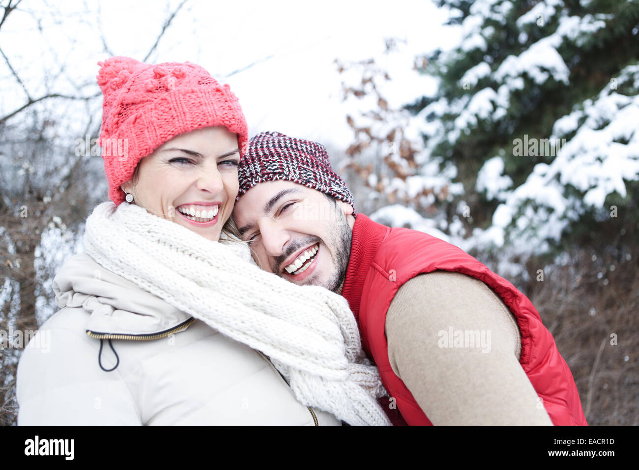 Happy young couple standing laughing in winter in snow Stock Photo