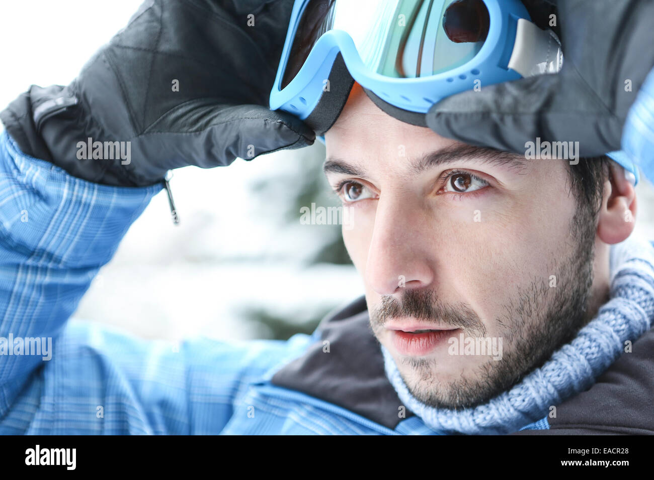 Man in ski holiday putting on his ski googles in winter Stock Photo