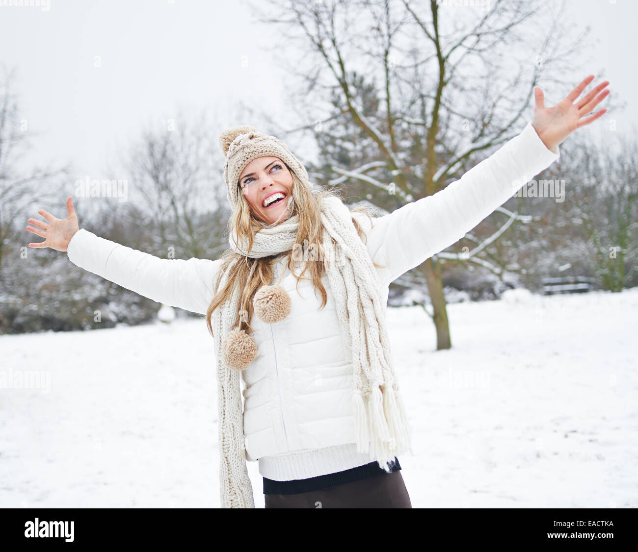 Happy woman standing in winter snow with her arms stretched out Stock Photo