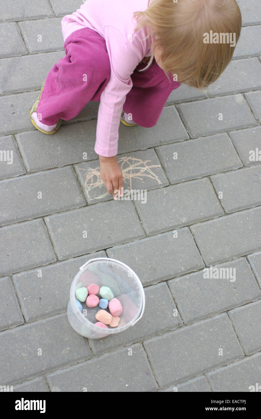 Little girl painting with crayon on the pavement Stock Photo - Alamy