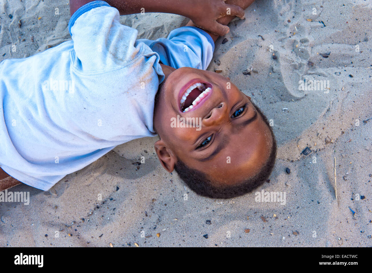Malagasy Boy lying on the ground and smiling, Betany village, Morondava, Toliara province, Madagascar Stock Photo