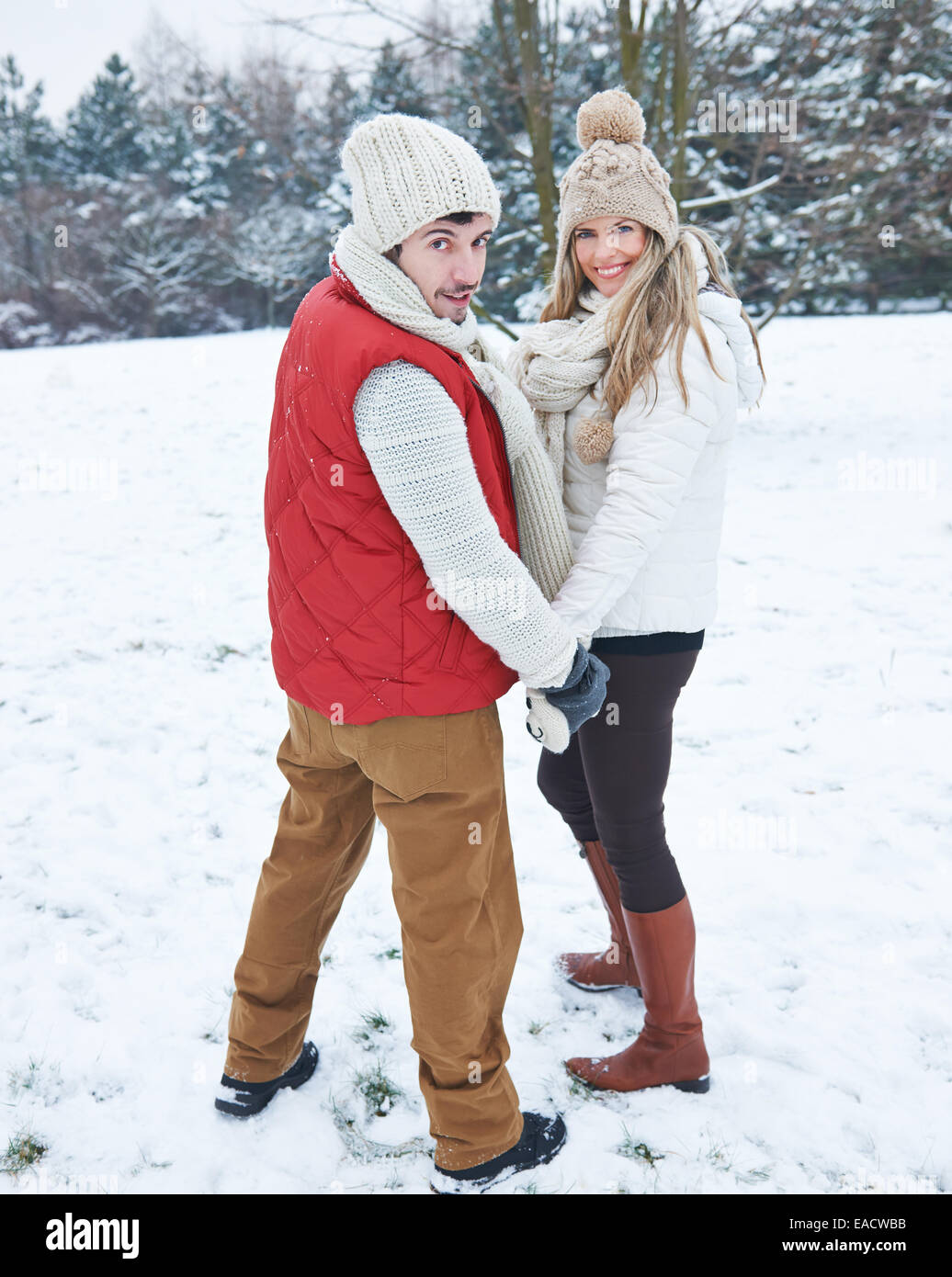 Happy couple hiking together through snow in winter Stock Photo