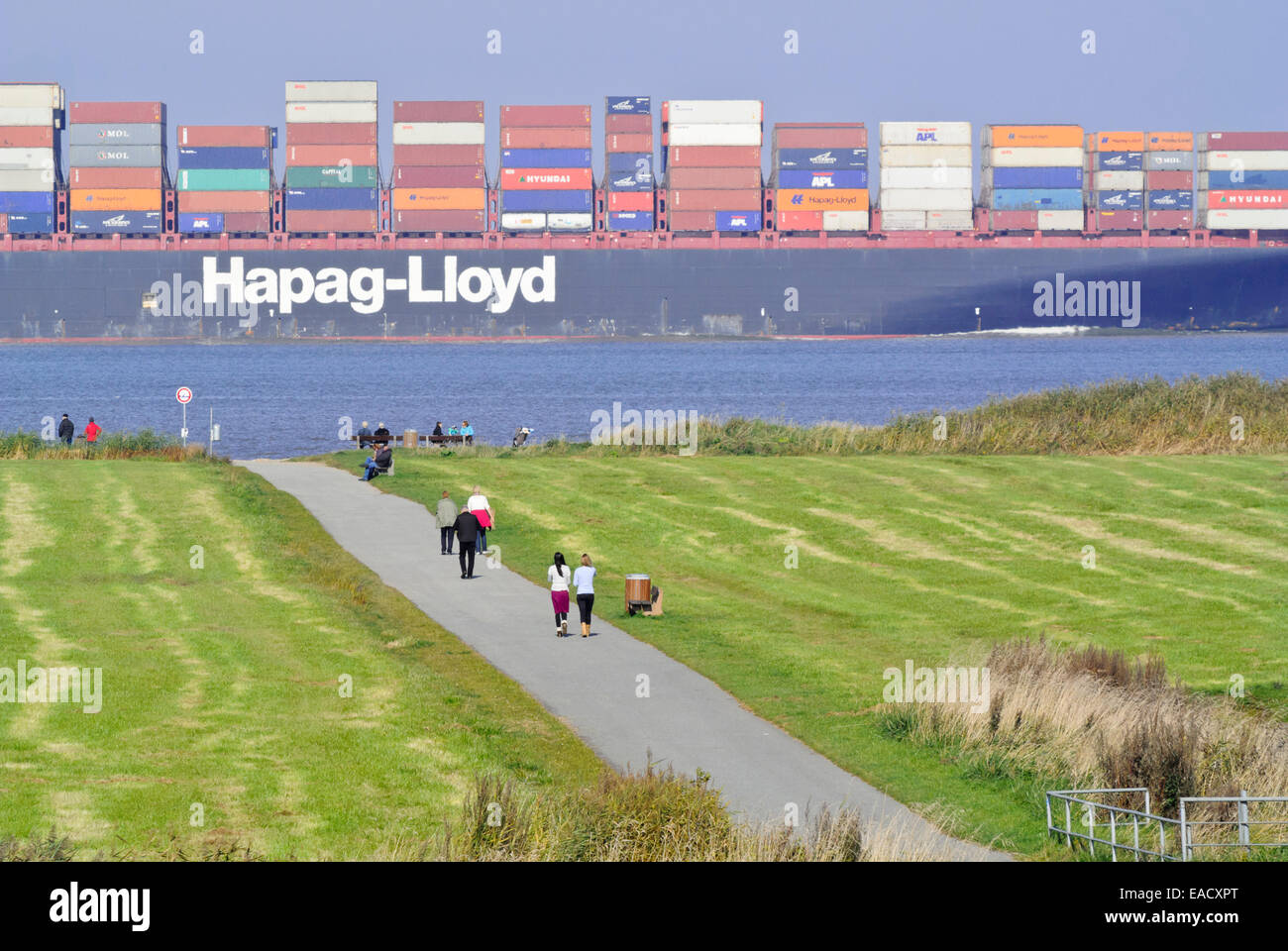Promenaders and container ship at Elbe River Mouth near Otterndorf, Germany Stock Photo