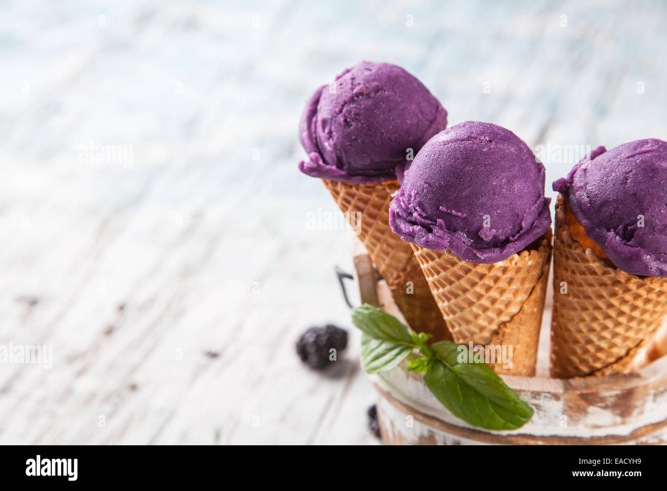 Studio photo of ice cream scoops in waffle cones. Served on wooden ...