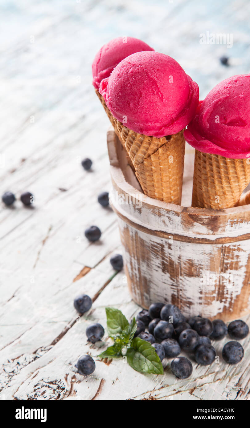 Studio photo of ice cream scoops in waffle cones. Served on wooden ...