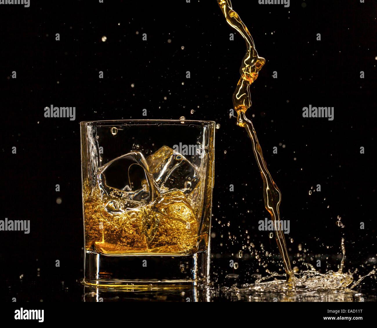 Pouring whiskey into glass, isolated on black background Stock Photo