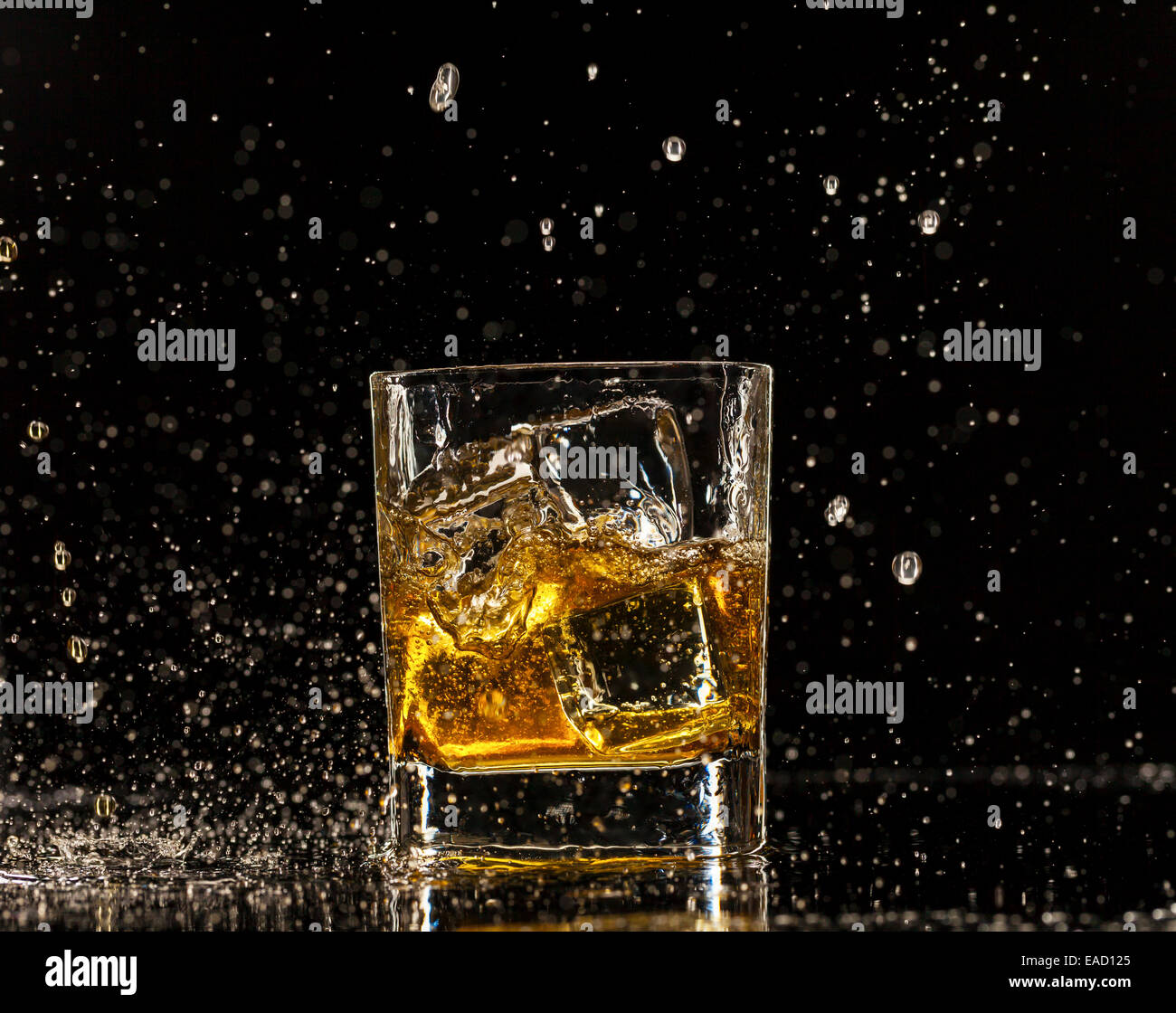 Whiskey splashing around glass, isolated on black background Stock Photo