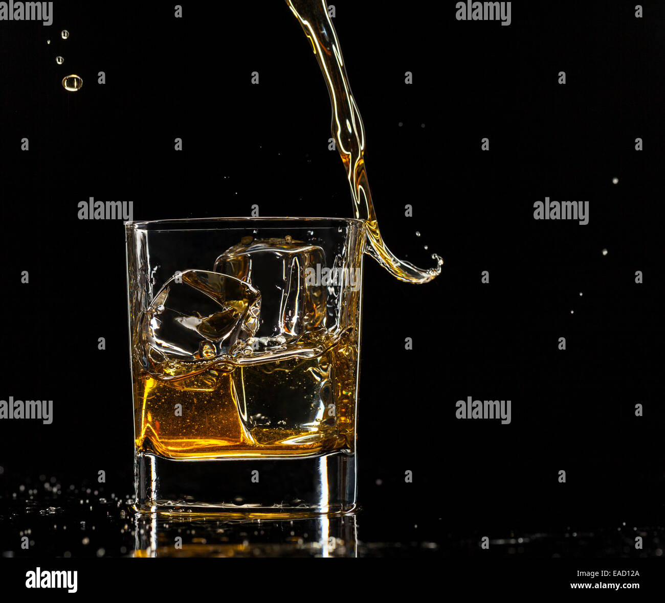 Pouring whiskey into glass, isolated on black background Stock Photo