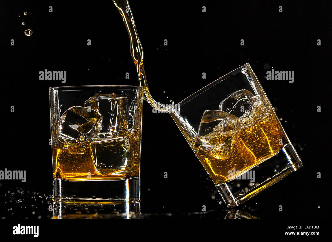 Pouring whiskey into glasses, isolated on black background Stock Photo