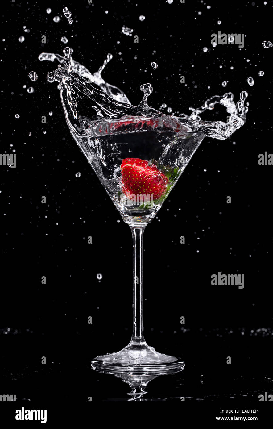 Martini drink splashing out of glass, isolated on black background