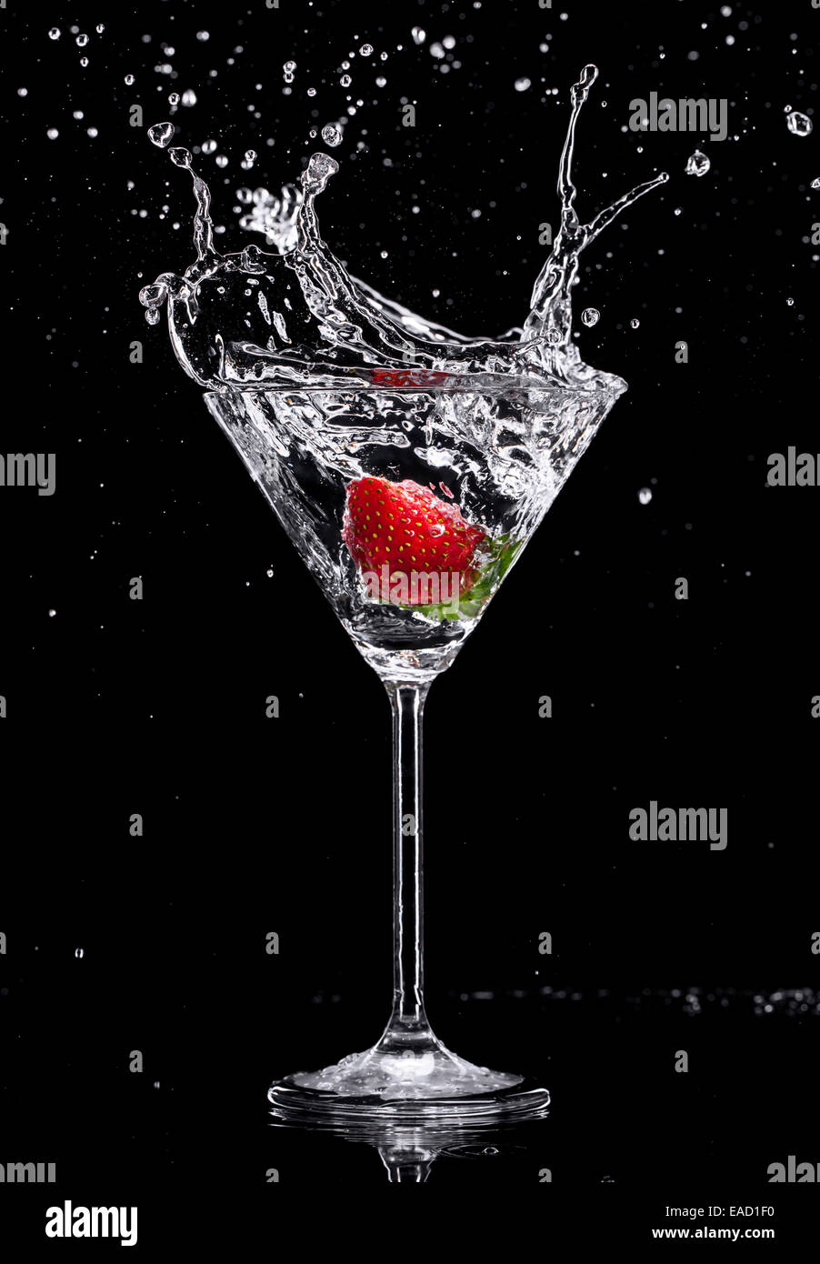 Martini drink splashing out of glass, isolated on black background