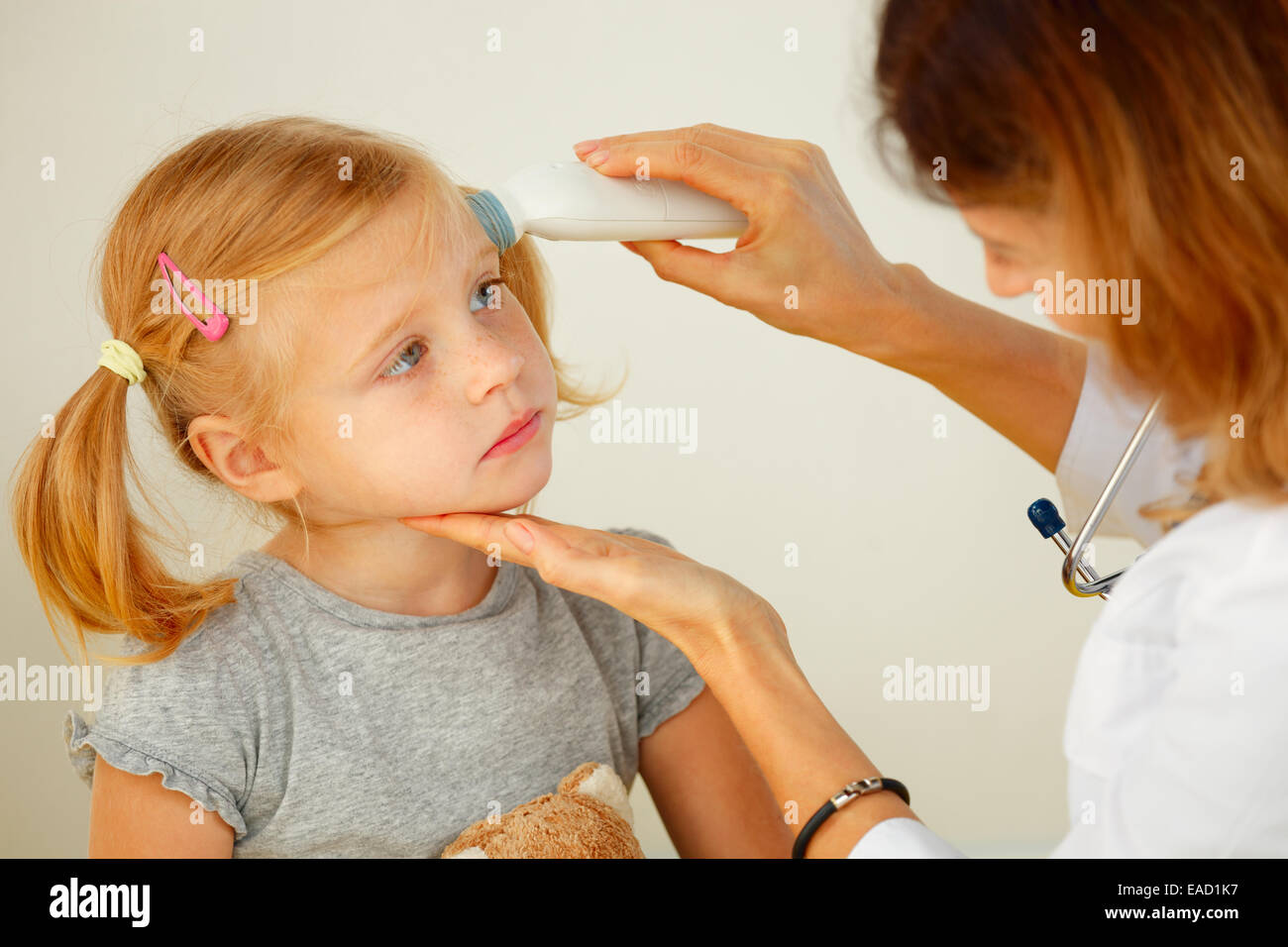 Pediatrician taking temperature with professional thermometer. Stock Photo