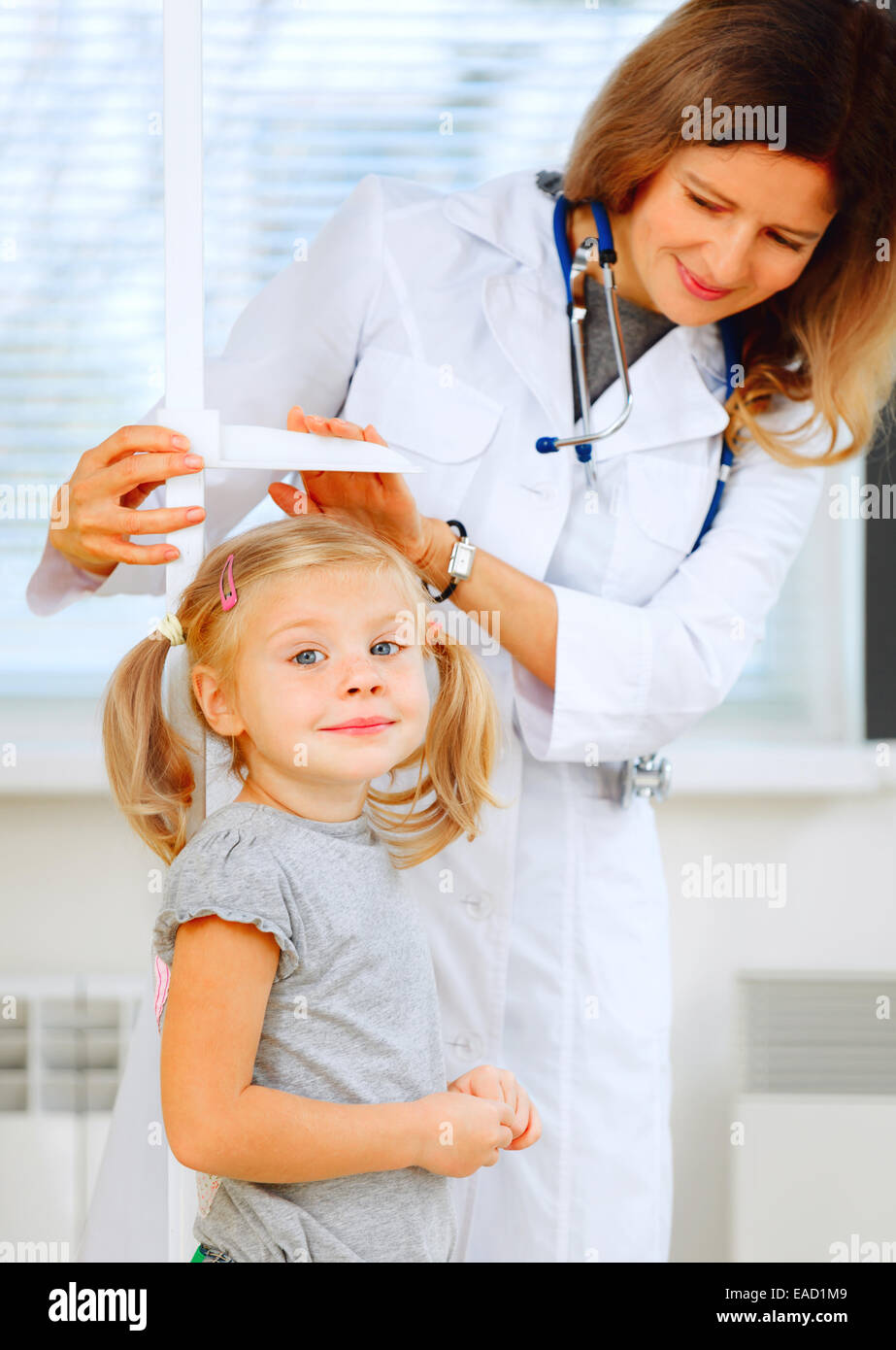 Doctor measuring height of a cute redhead girl. Stock Photo