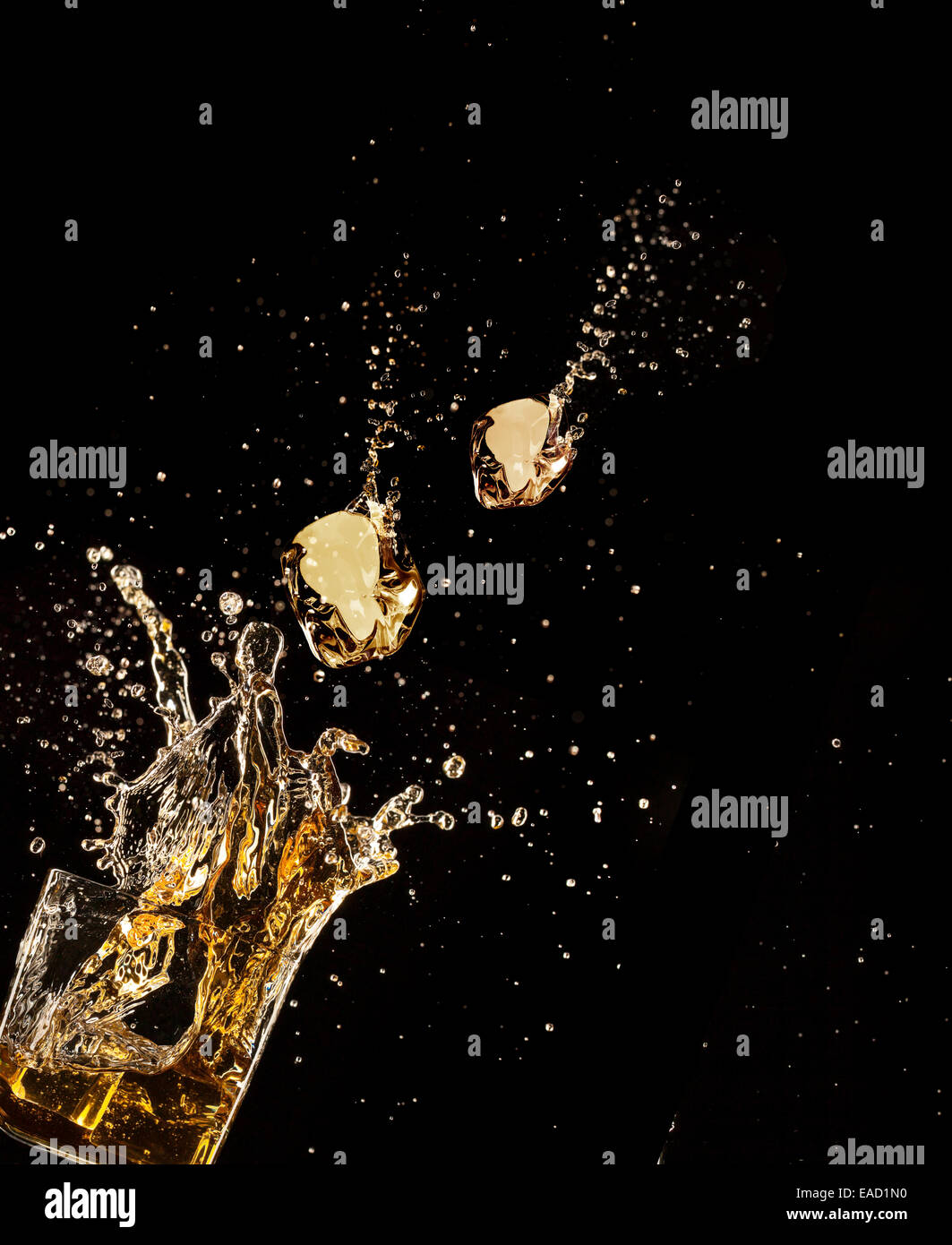 Isolated shot of whiskey splashing out of glass on black background Stock Photo