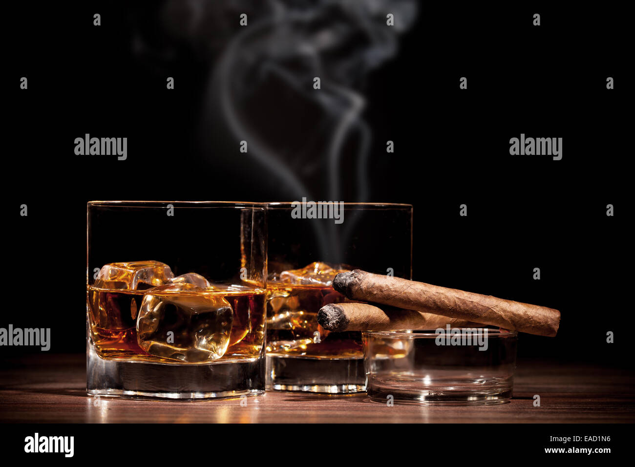 Whiskey drinks with smoking cigars on wooden table Stock Photo