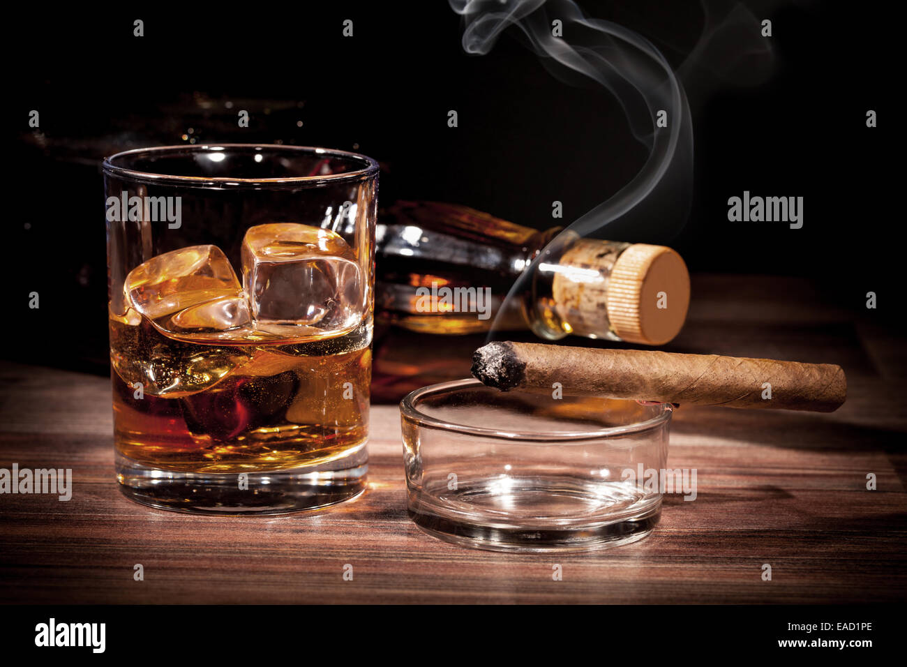 Whiskey drink with smoking cigar on wooden table Stock Photo