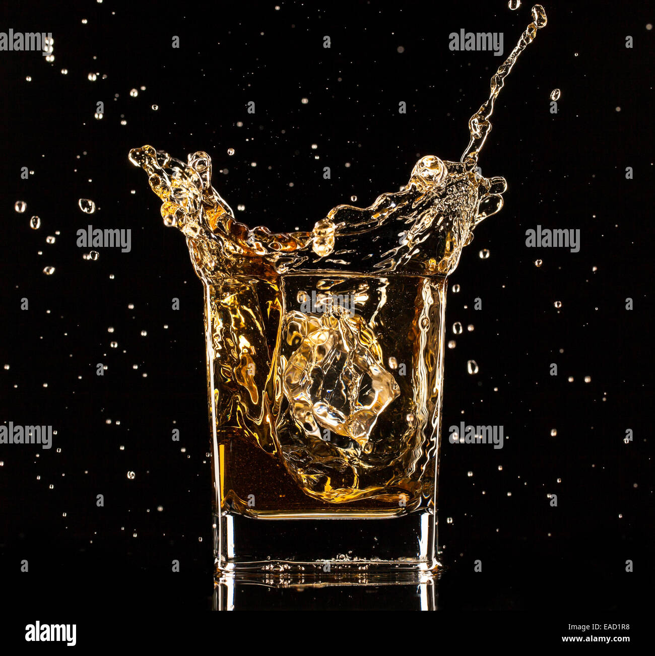 Isolated shot of whiskey splashing out of glass on black background Stock Photo