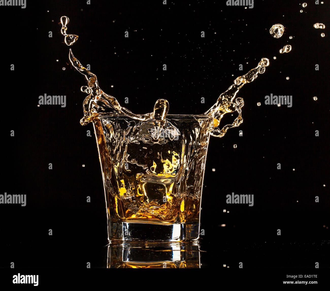 Glass of whiskey with splash, isolated on black background Stock Photo