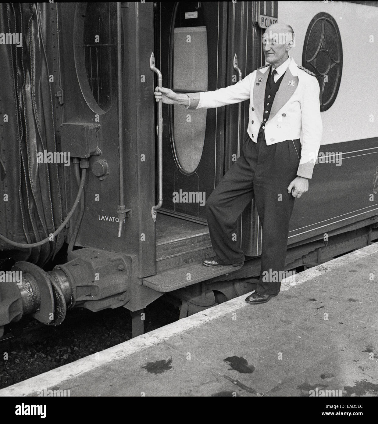 1950s, historical picture of the restaurant manager on the platform with the carriage train door open awaiting his Pullman guests or customers, Great Western, England. Stock Photo