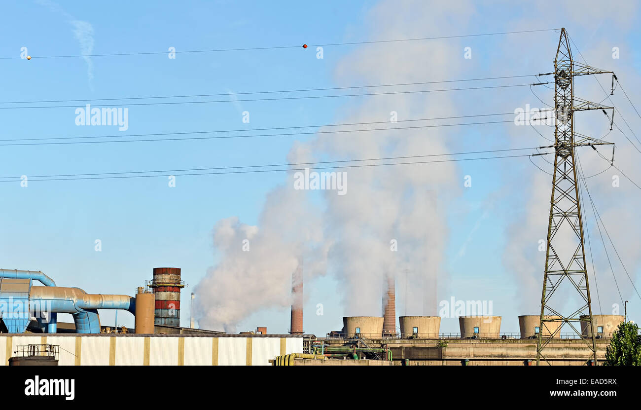 Early morning scene in industrial zone with steam coming from steam pipes of a factory and electrical pole Stock Photo