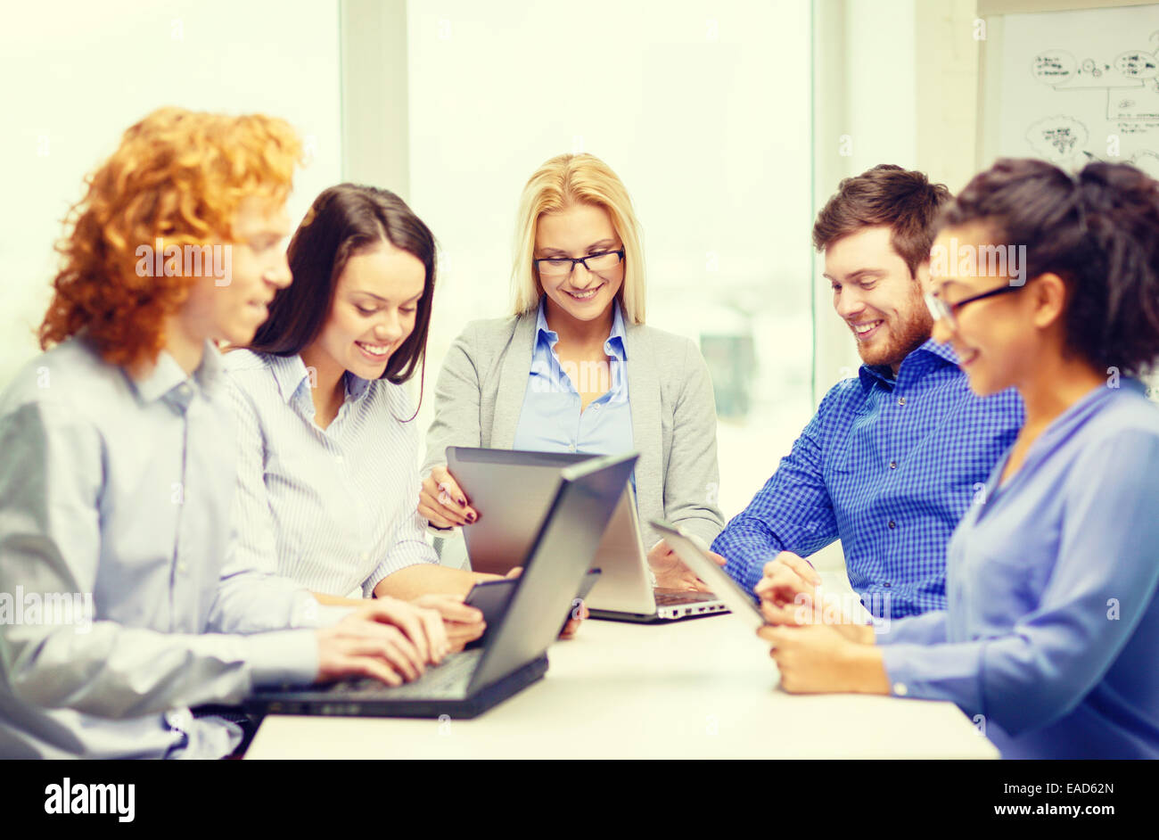 smiling team with laptop and table pc computers Stock Photo - Alamy