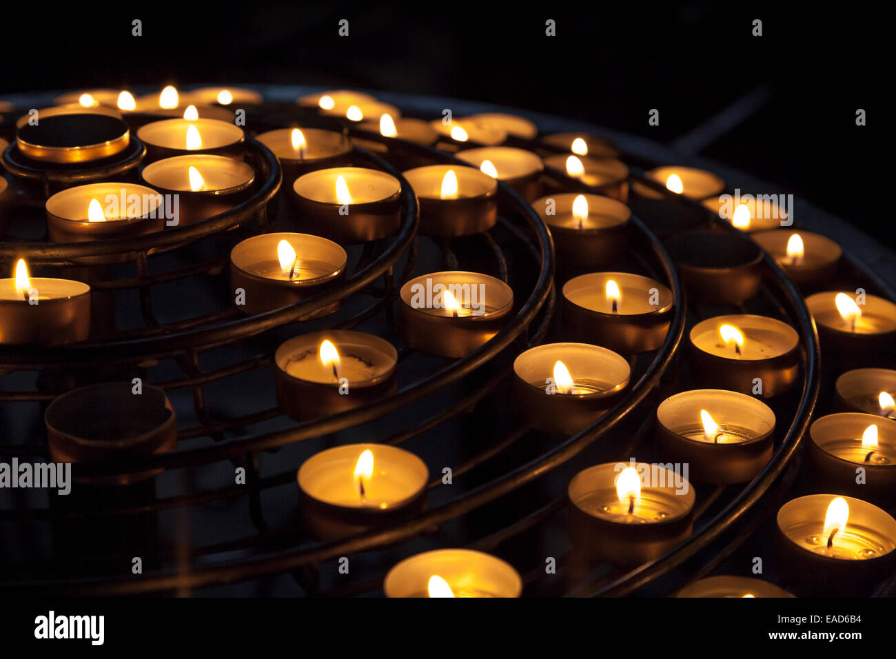 Small candles burn in dark interior of Catholic cathedral Stock Photo