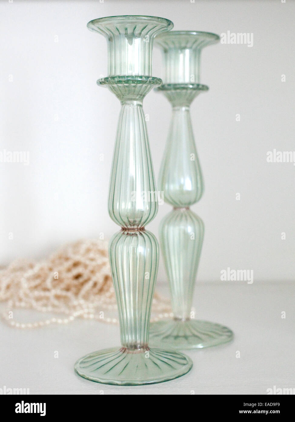 green glass candle stick holders and pearl necklace on shelf Stock