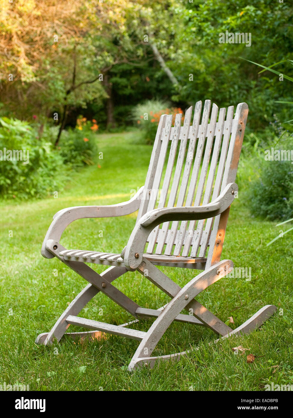 antique wooden rocking chair on lawn and country lane Stock Photo