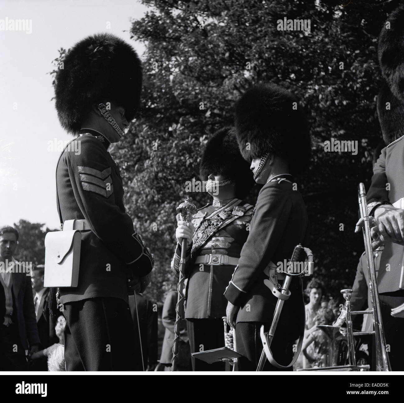 1960s historical, three beefeaters' or Royal Guardswith bearskin faux fur hats discuss. Stock Photo