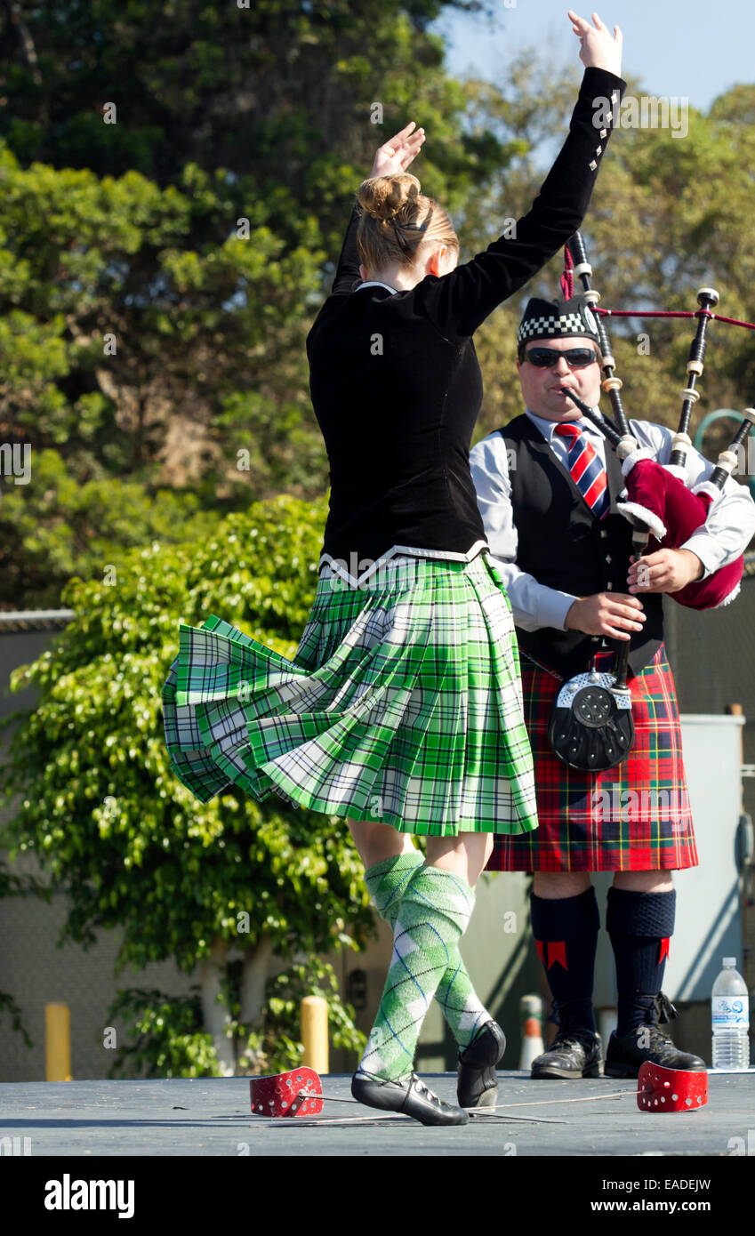 Dancer performing a traditional highland sword dance routine with a bagpipe player Stock Photo