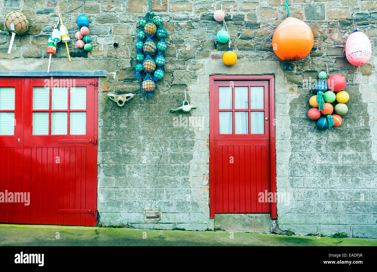 Colourful fishing floats decorate a wall at a harbour / harbor. Stock Photo