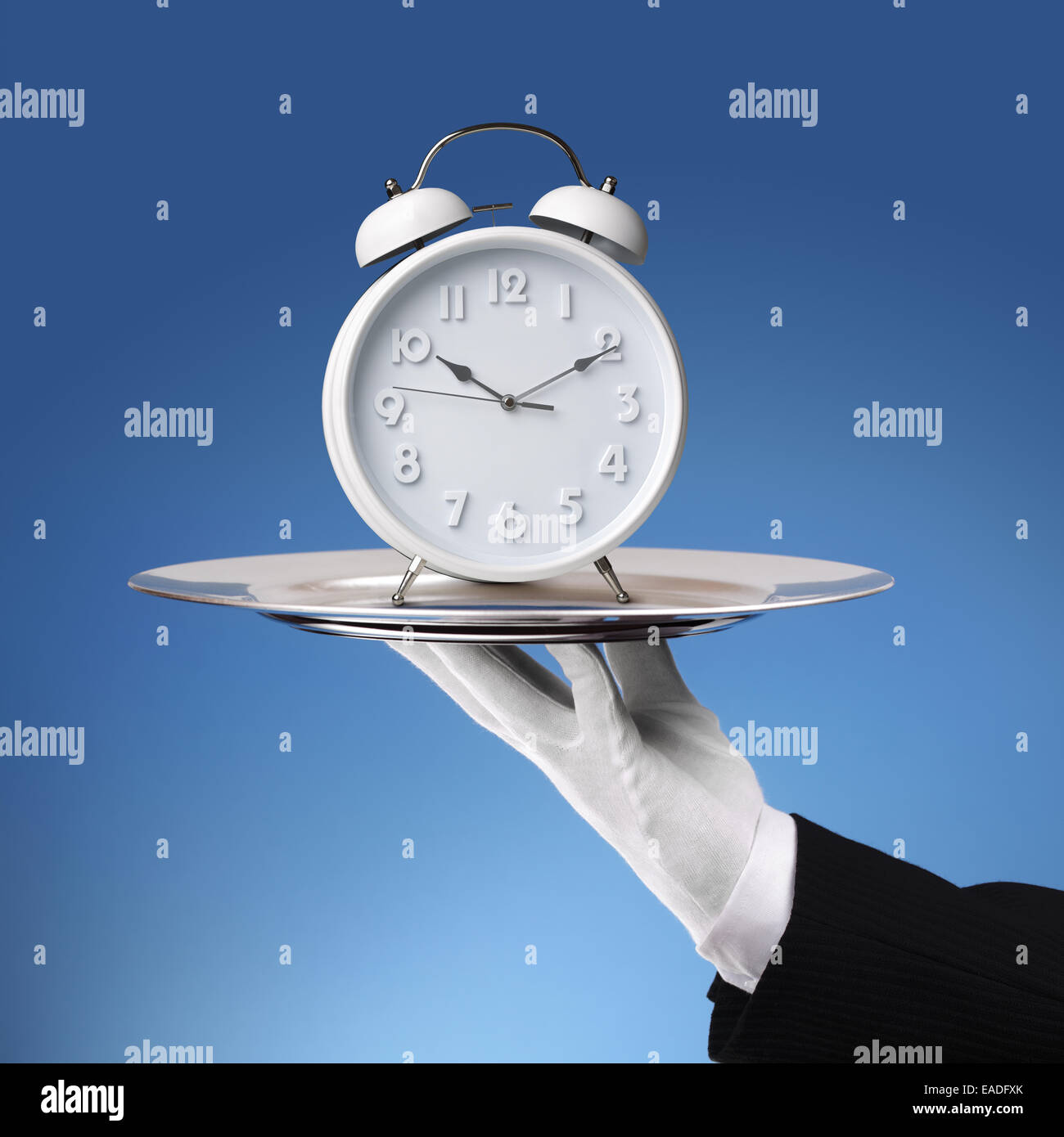 Butler holding silver tray with a alarm clock Stock Photo