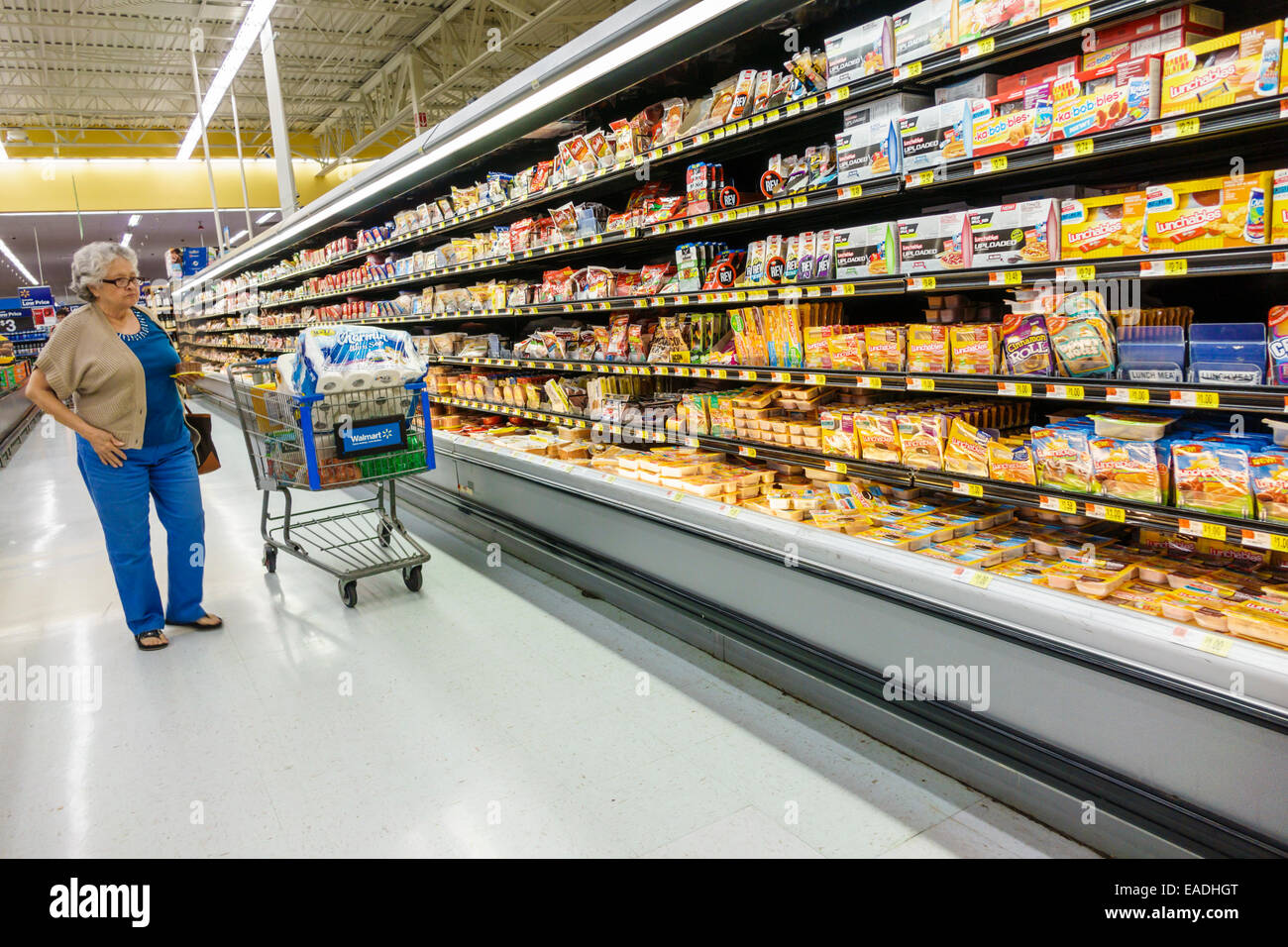 Miami Florida,Walmart Supercenter grocery supermarket food,refrigerated display case sale lunch meat aisle,senior citizen woman store cart trolley Stock Photo