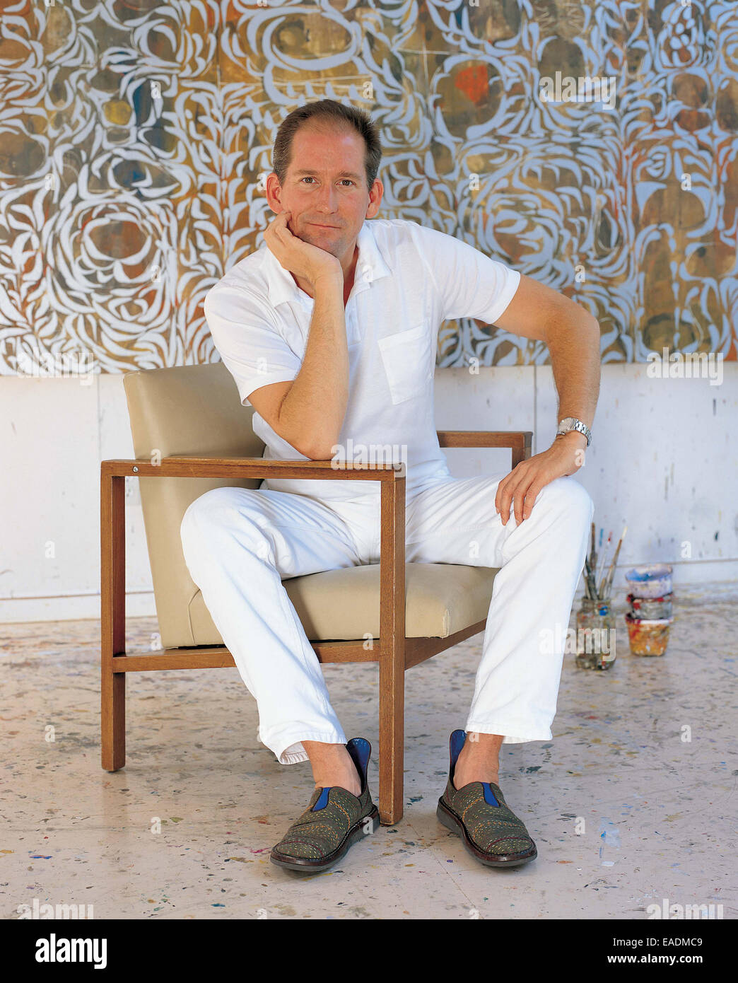 artist poses in front of painting in studio Stock Photo