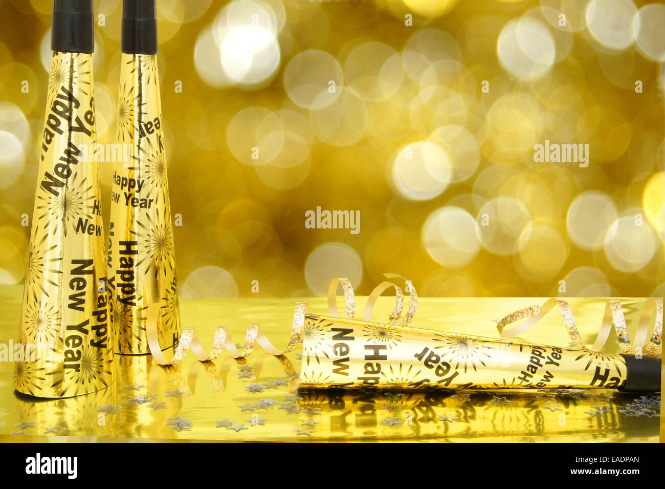 New Years Eve noisemakers and confetti with twinkling gold light ...