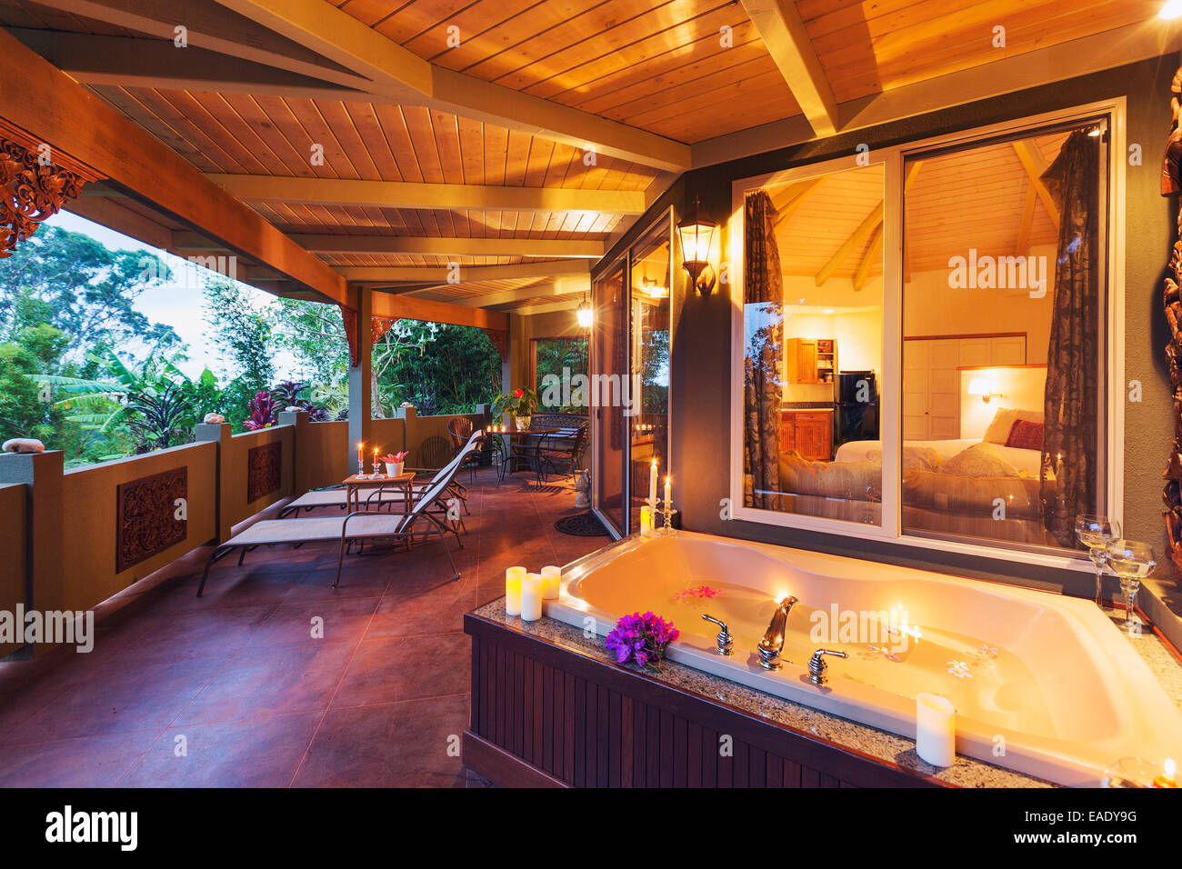 Beautiful Romantic Deck on Tropical Home with Bathtub, Candles, and Flowers at Sunset Stock Photo