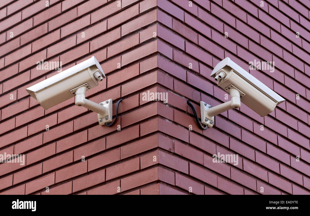 Two security cameras on the brick wall overlooking opposite sides Stock