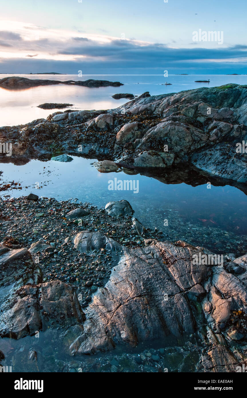 Sun rising over a rocky ocean coastline Stock Photo - Alamy