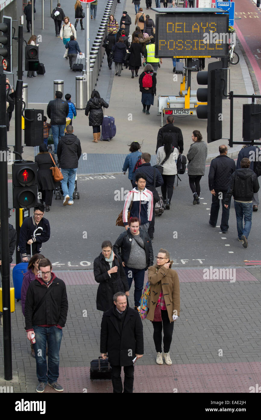Commuters outside  Kings Cross station with delays possible sign Stock Photo