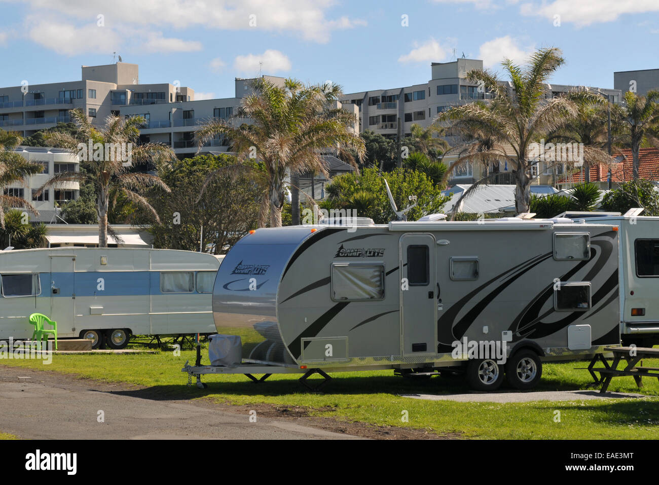 Large two axle caravan parked in caravan park located among apartment buildings and palm trees. Stock Photo
