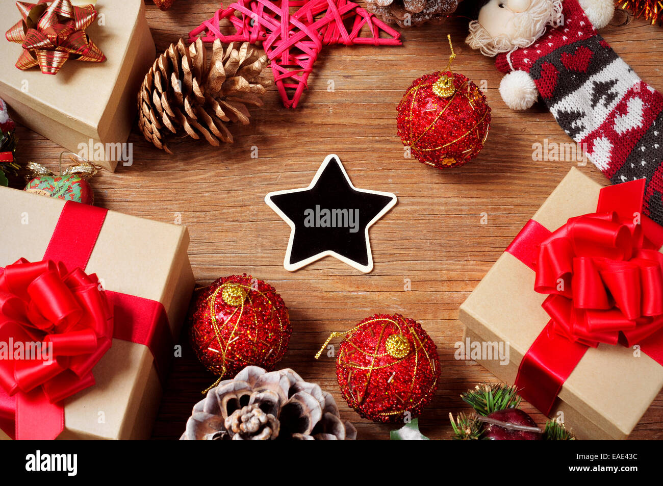 a pile of gifts and christmas ornaments, such as christmas balls and stars, on a rustic wooden table with a blank heart-shaped c Stock Photo