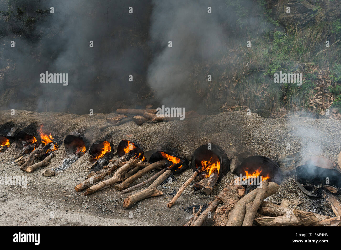 Gravel and hot tar being mixed on open fires at a road construction site, Shimla, Himachal Pradesh, India Stock Photo