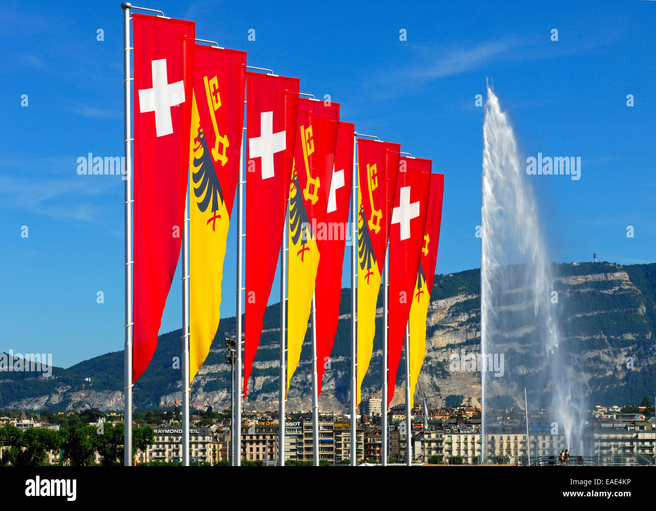 Flags of the Swiss Confederation and the Canton of Geneva on the promenade of Lake Geneva with the Jet d'Eau fountain and the Stock Photo