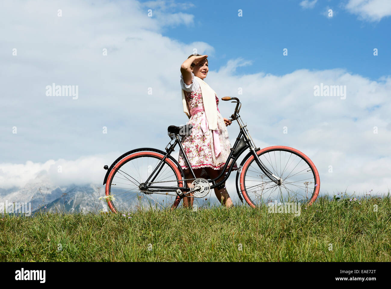 Woman wearing a dirndl with an old bicycle, Igls, Innsbruck, Tyrol, Austria Stock Photo